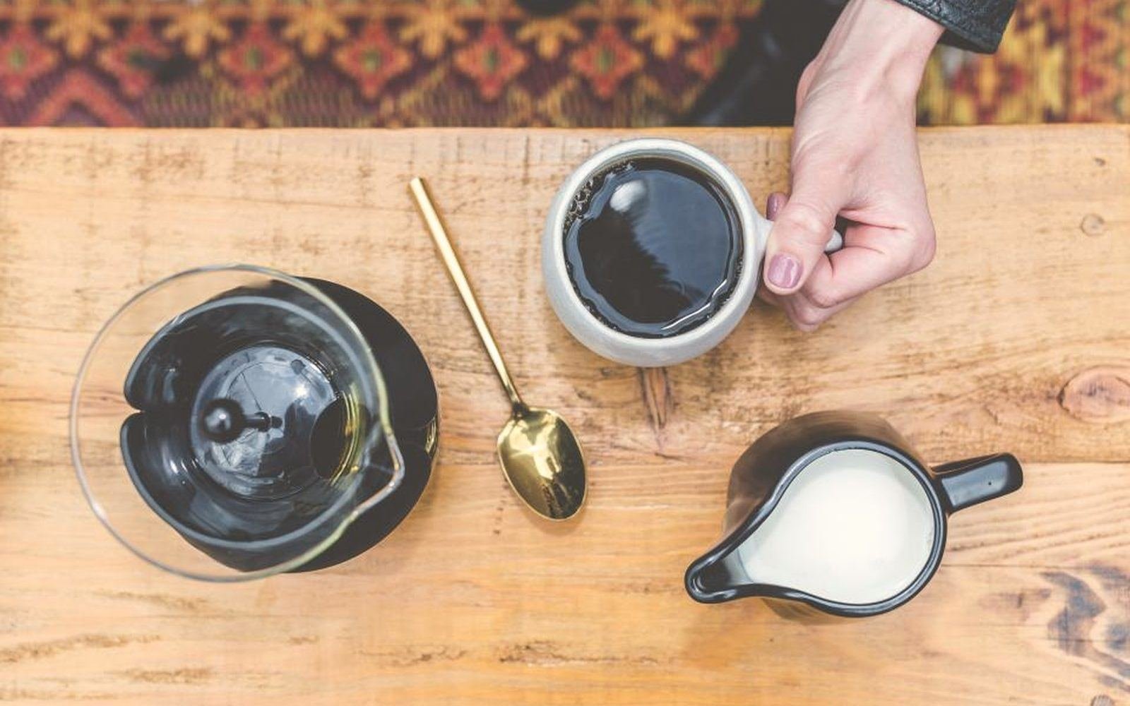 Coffee being poured into a cup on a wooden table